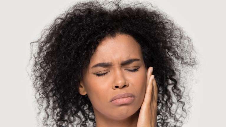 woman in pain holding her left cheek